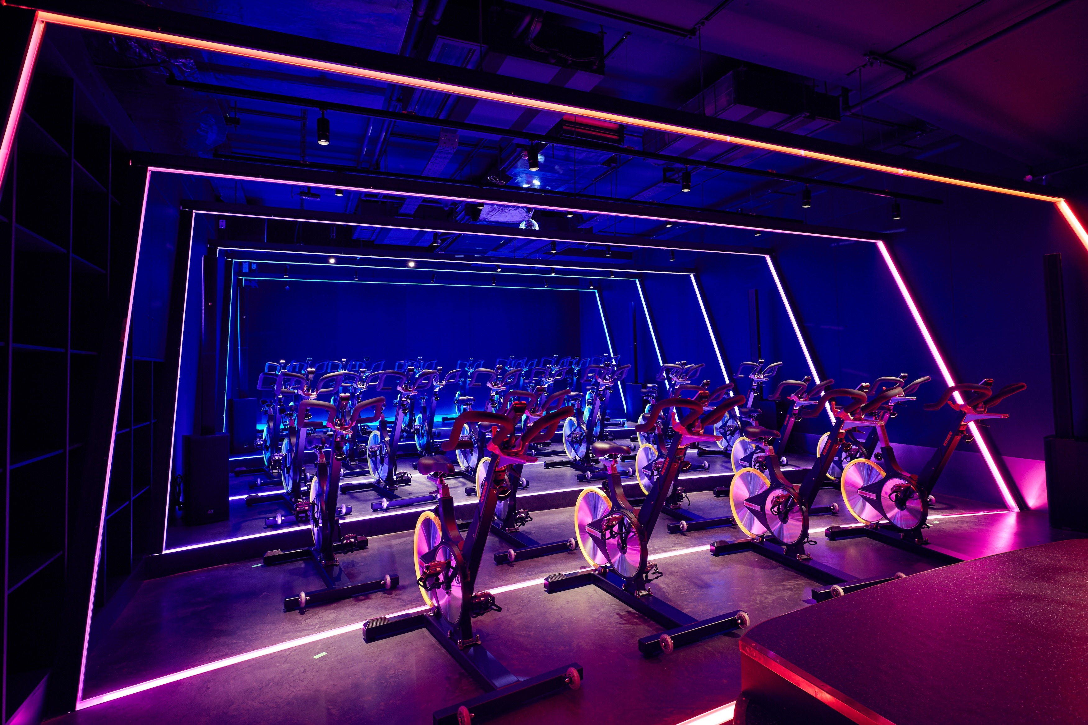 KXU Gym London indoor cycling studio with dynamic LED architectural lighting design for immersive fitness experience